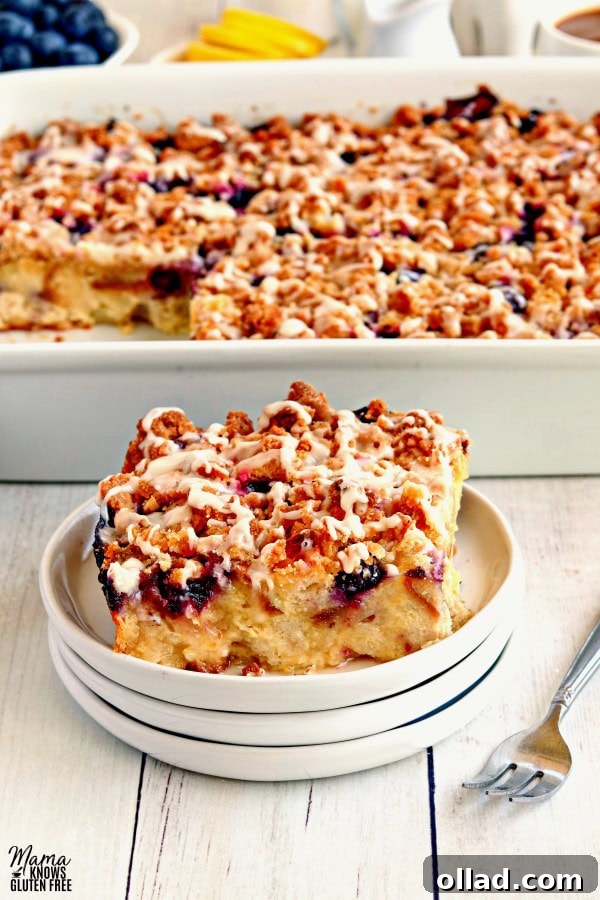 A delectable slice of gluten-free blueberry lemon breakfast casserole served on a white plate, with the rest of the casserole visible in the background, showcasing its inviting texture and golden crumb topping.