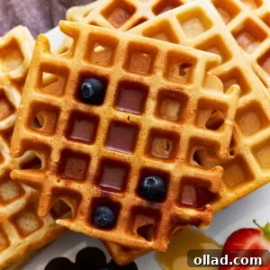 overhead view of a stack of gluten-free waffles with syrup and blueberries.
