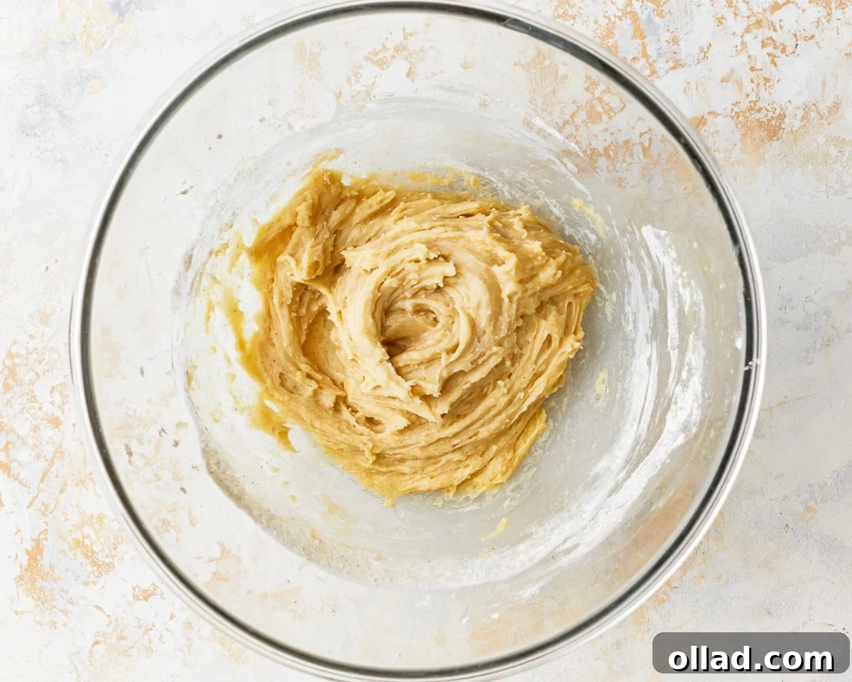 A thick, partially mixed batter in a glass bowl, showing the initial combination of wet and dry ingredients.