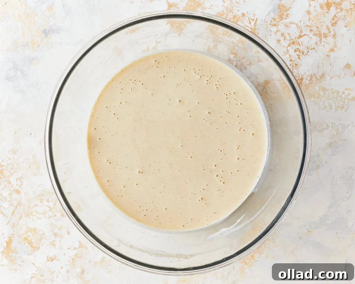 A smooth, pourable waffle batter in a glass bowl after all ingredients have been combined and milk has been added.