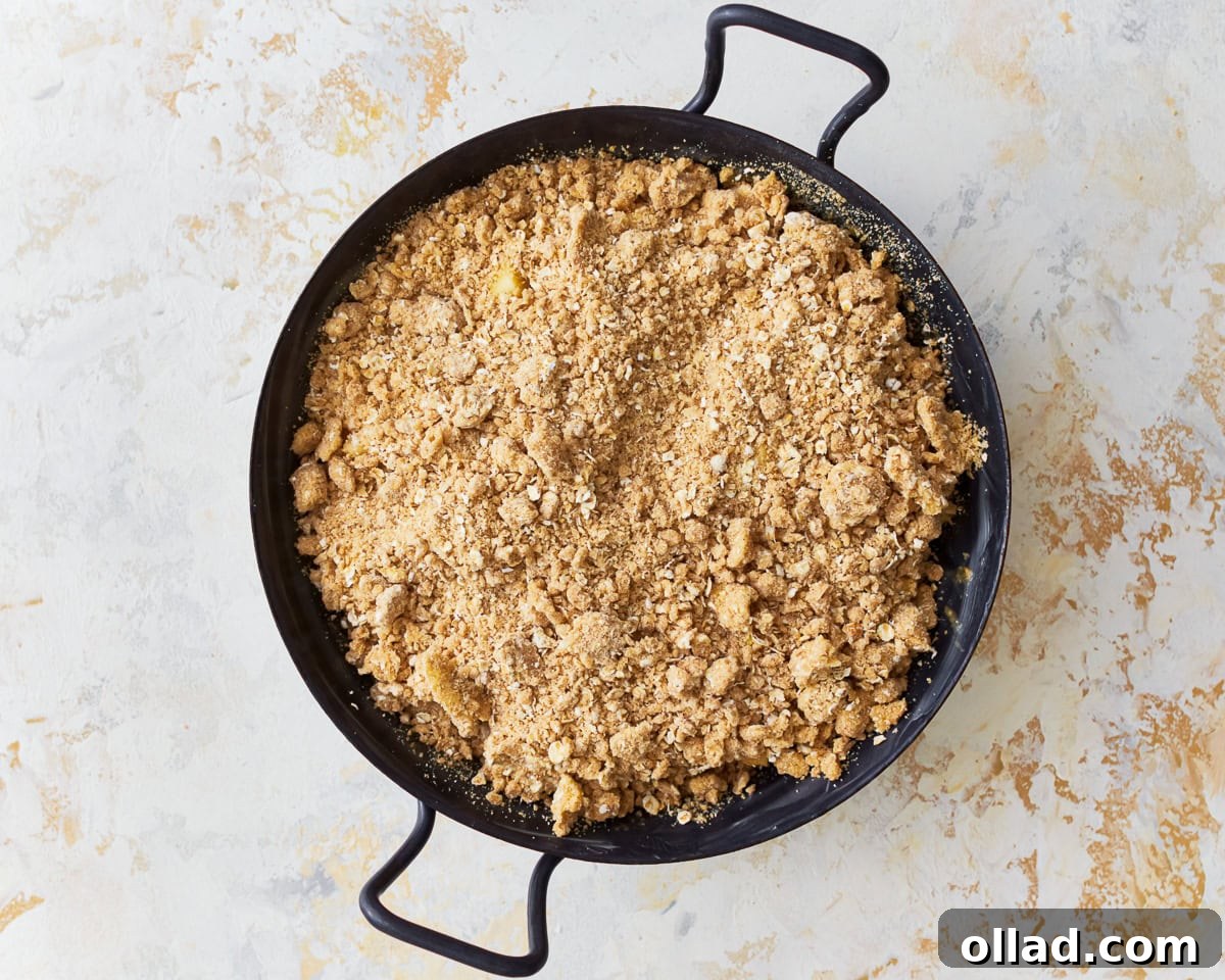 Wholesome Gluten-Free Apple Crumble 9 The apple filling in the baking dish is topped with the crumbly oat topping, ready for baking, showing a uniform layer of the crisp mixture.