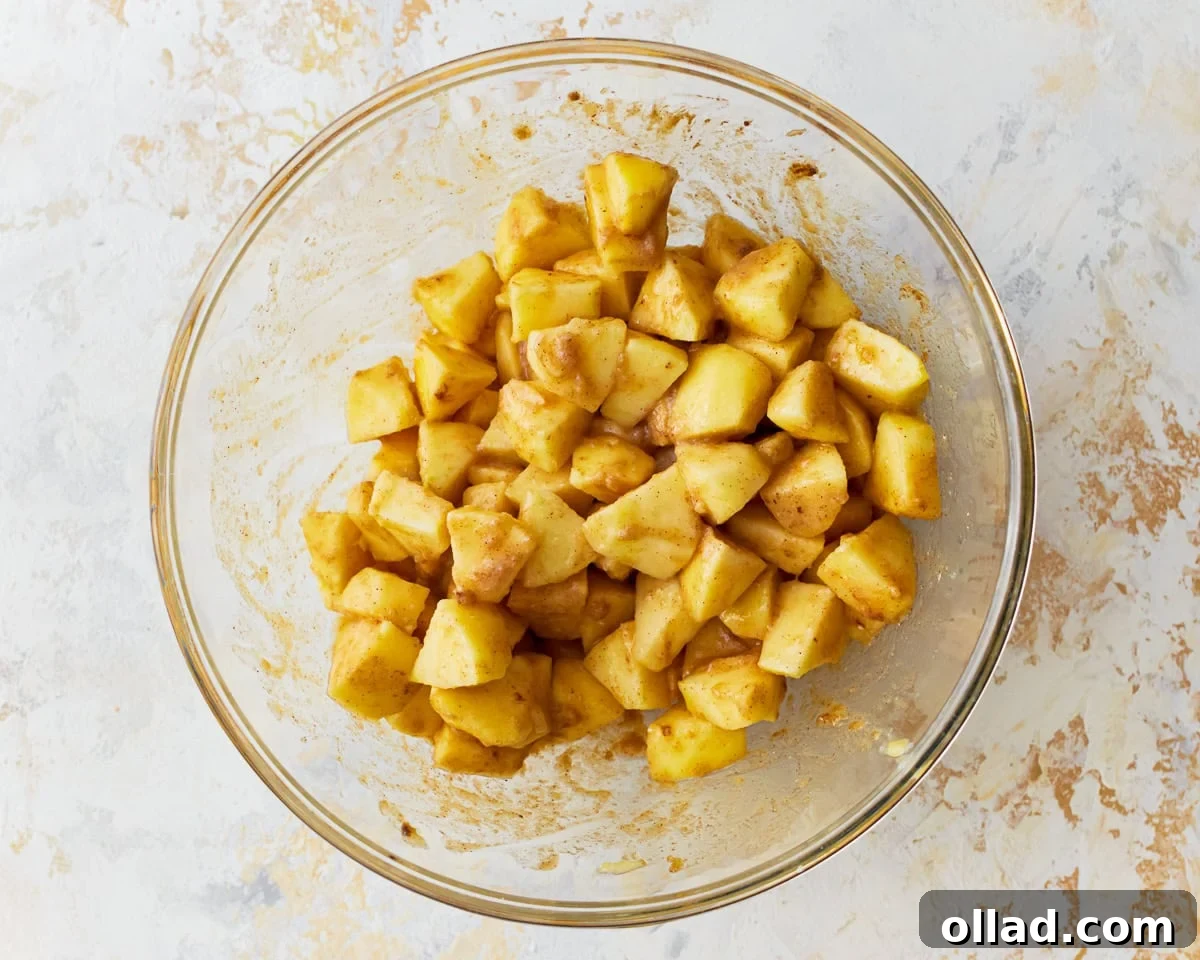 Wholesome Gluten-Free Apple Crumble 7 Freshly peeled and chopped apples are in a large glass mixing bowl, ready for the gluten-free apple crisp filling, alongside a lemon and other ingredients.