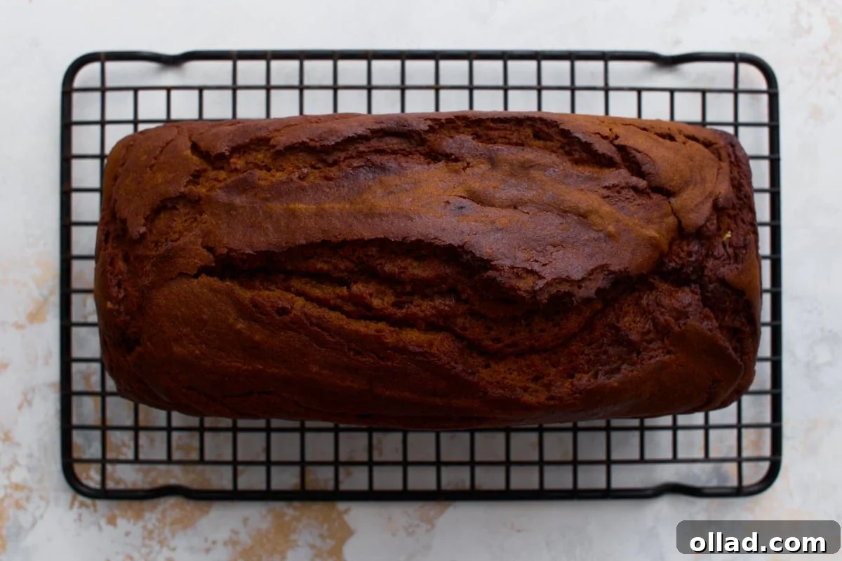 Freshly baked gluten-free pumpkin bread cooling on a wire rack, with a crackly top.