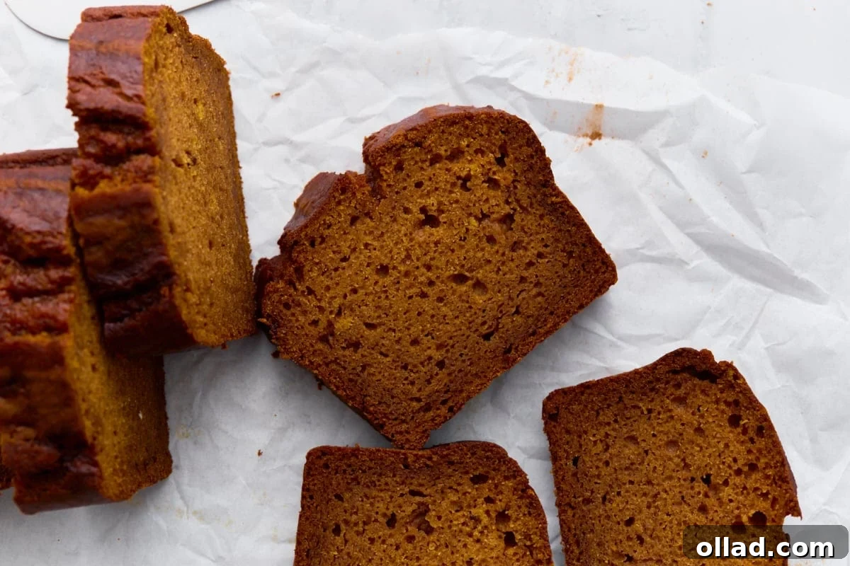 Close-up slices of gluten-free pumpkin bread laid out on parchment, highlighting the moist texture.