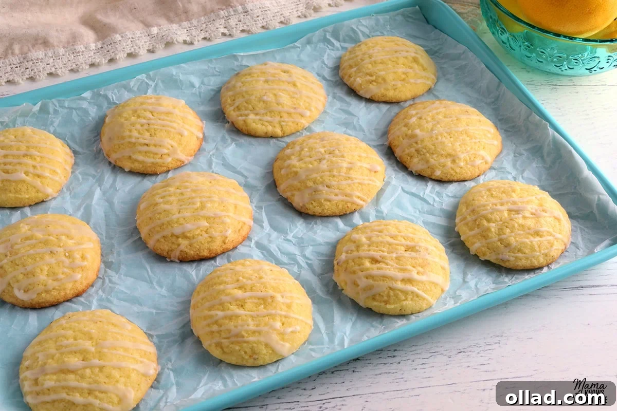 gluten-free lemon cookies on a blue cookie sheet with a bowl of lemons in the background