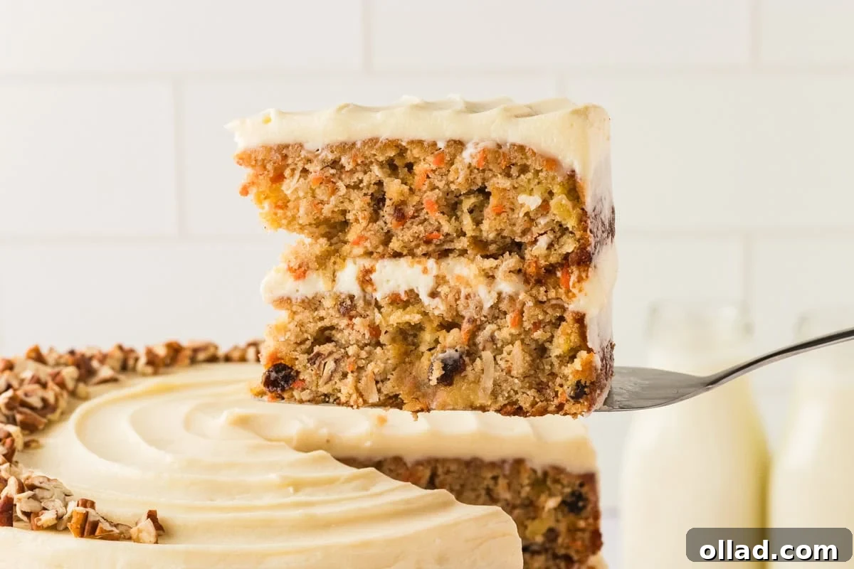A close-up of a slice of gluten-free carrot cake being lifted from the whole cake with a cake server.