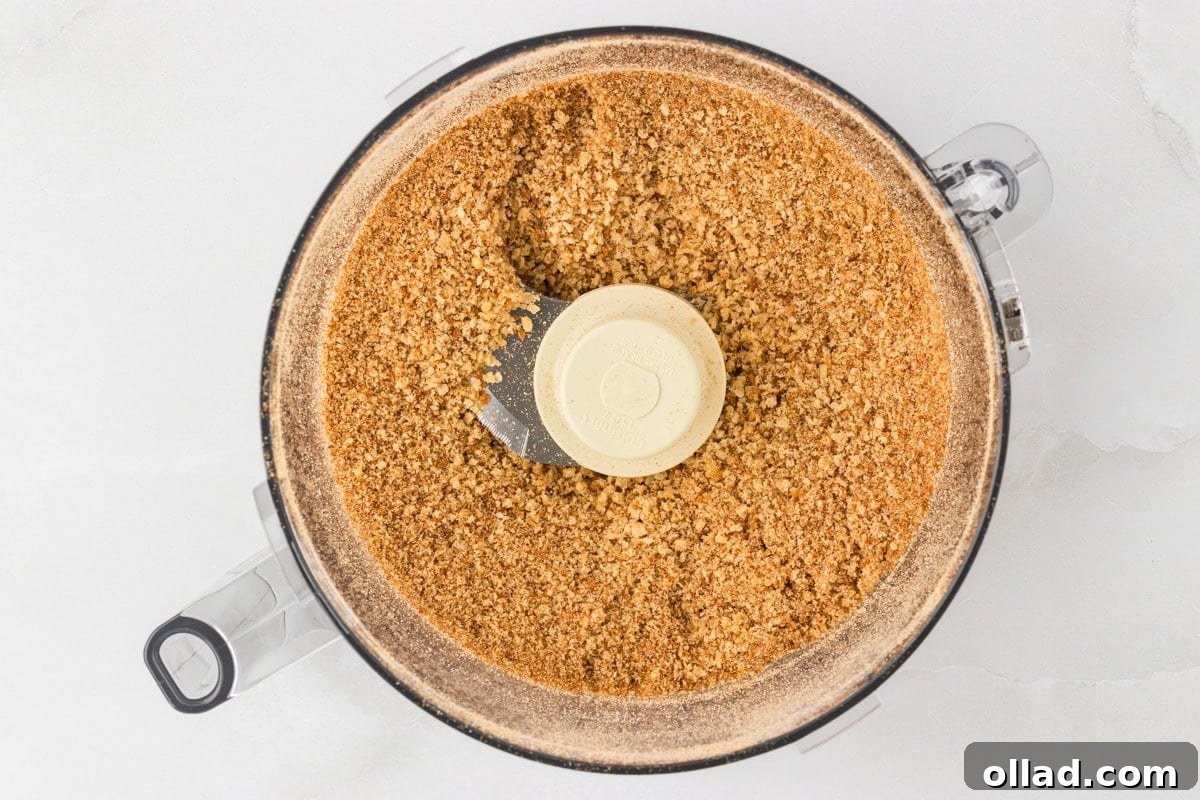 Top-down view of finely ground gluten-free breadcrumbs inside a food processor after blending.