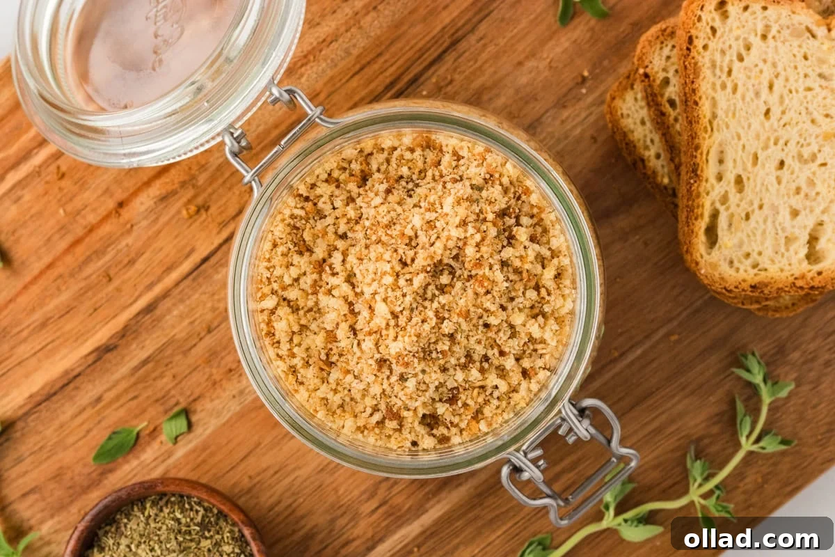 Overhead view of a glass jar filled with gluten-free breadcrumbs, surrounded by fresh herbs and slices of gluten-free bread on a wooden board.