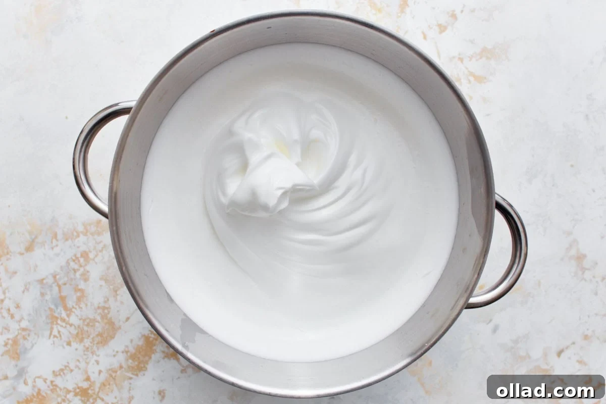 Cloud-Light Gluten-Free Angel Food Cake 7 Glossy, soft peak meringue whipped from egg whites, sugars, and extracts in a stainless steel mixing bowl.