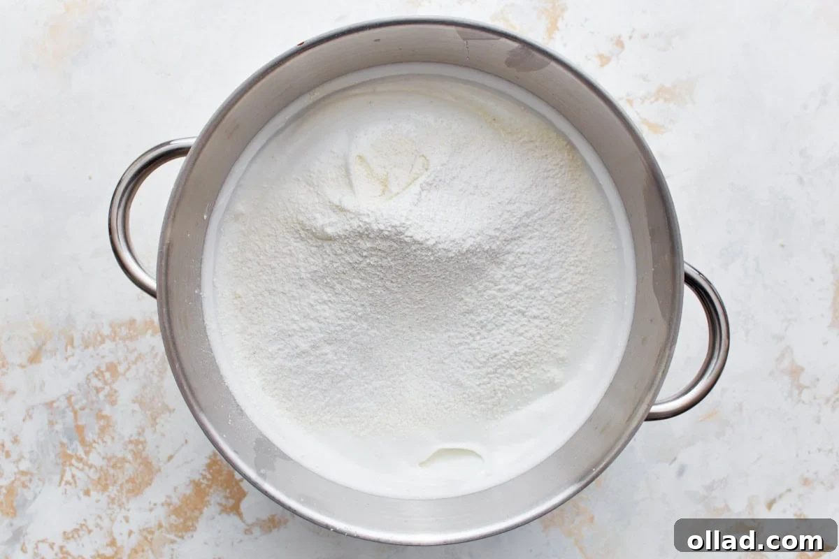 Cloud-Light Gluten-Free Angel Food Cake 8 Gluten-free flour mixture gently sprinkled over the top of the fluffy, whipped egg white meringue in a stainless steel mixing bowl.