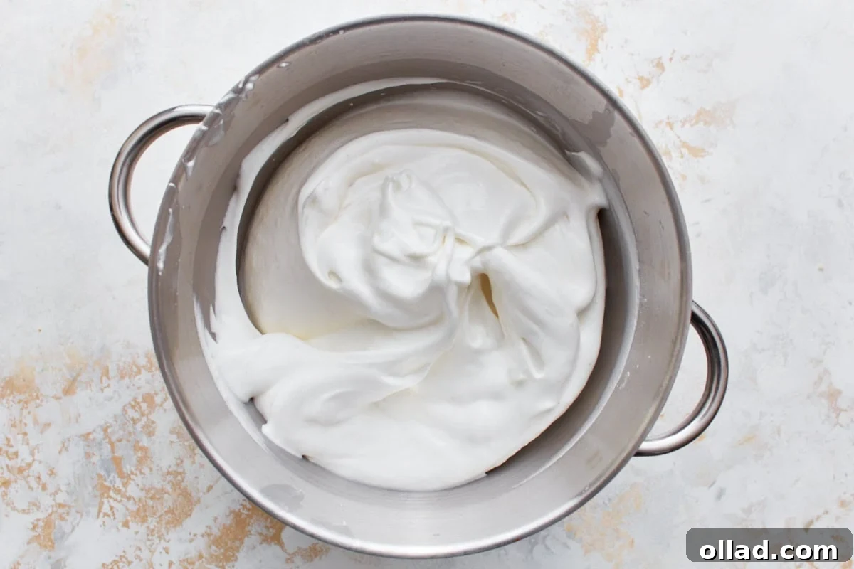 Cloud-Light Gluten-Free Angel Food Cake 9 Light and airy whipped gluten-free angel food cake batter filling a stainless steel mixing bowl, ready for baking.