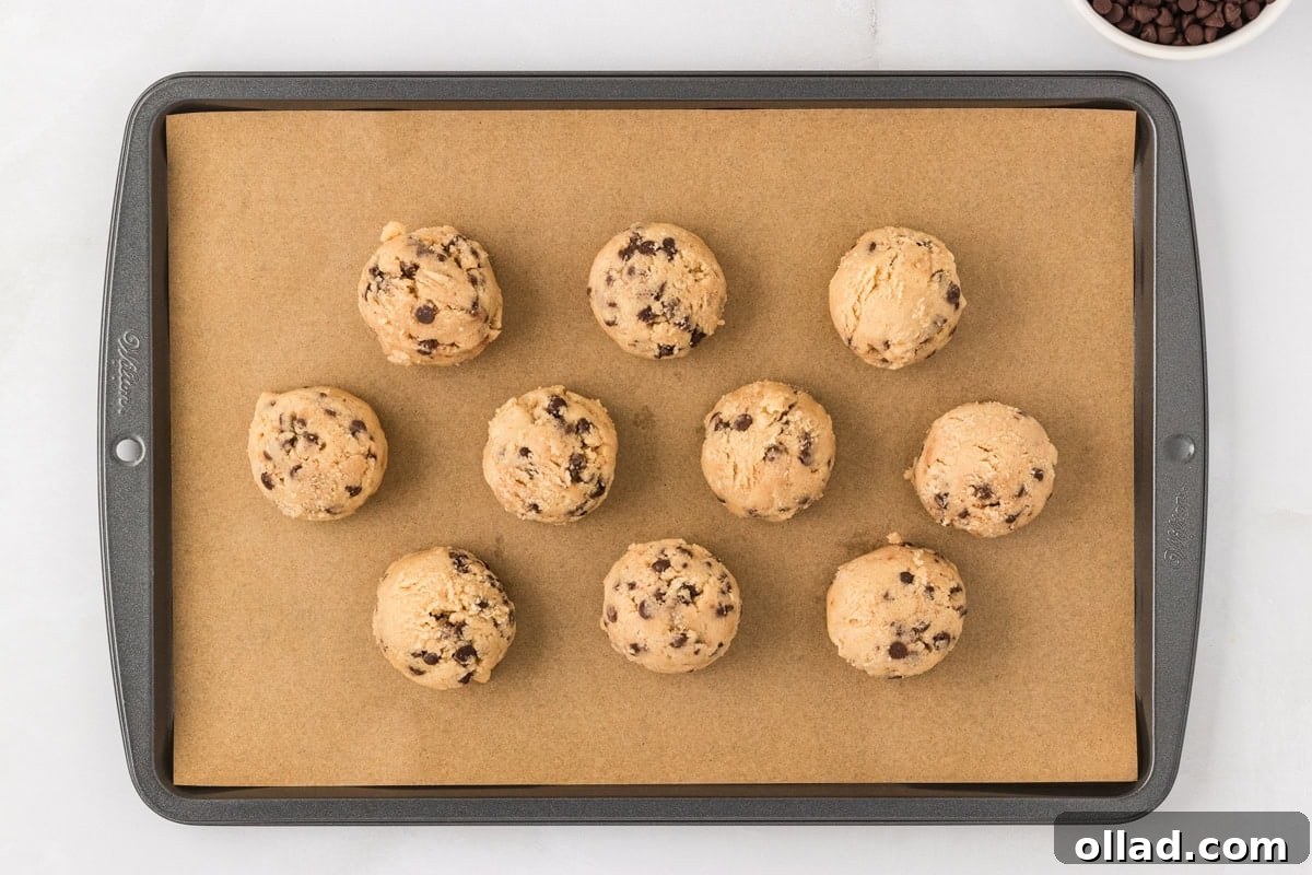 Irresistible Gluten-Free Cookie Dough 9 Neatly arranged scoops of gluten-free edible cookie dough dot a parchment-lined baking sheet, awaiting their chill in the freezer to firm up before serving.