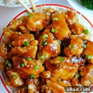 A perfectly portioned bowl of gluten-free apricot chicken, featuring tender chicken pieces coated in a rich sauce. The dish is presented with chopsticks, and in the background, fresh broccoli and white rice hint at a complete and healthy meal.