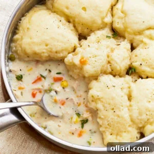 A close-up view of a steaming bowl of gluten-free chicken and dumplings, showcasing the tender chicken, fluffy dumplings, and rich, creamy broth. Garnish with fresh herbs for an inviting presentation.