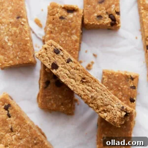 Simple & Delicious Homemade Gluten-Free Granola Bars 3 Homemade gluten-free granola bars stacked on parchment paper, showing their golden brown texture and chocolate chip details.