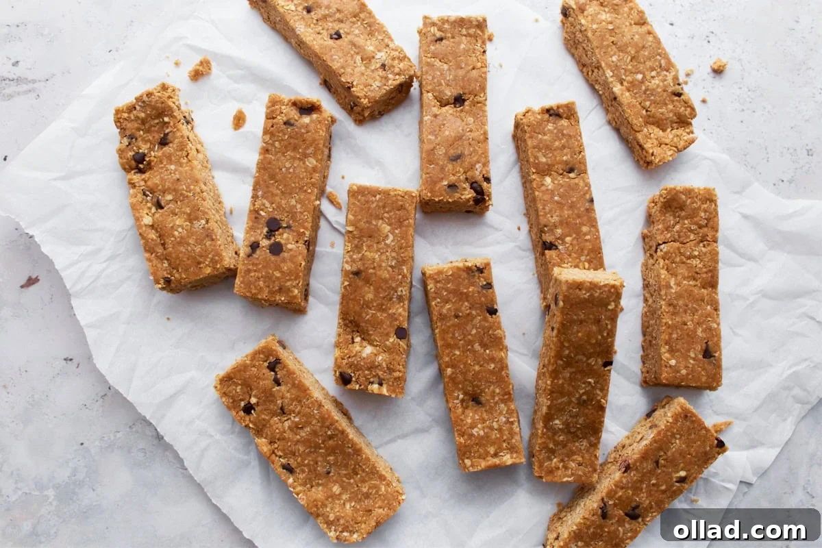 Simple & Delicious Homemade Gluten-Free Granola Bars 9 A collection of gluten-free granola bars spread out on parchment paper, highlighting their uniform shape and chocolate chip accents, with a few stacked.