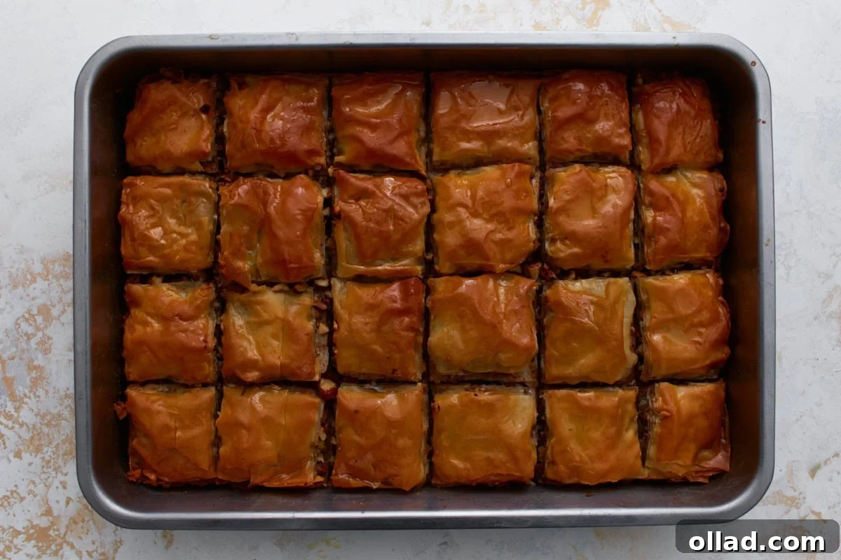 Hot baked gluten-free baklava in a pan after pouring honey syrup over the top.
