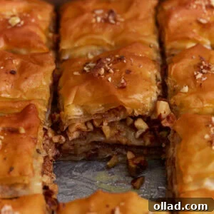 Gluten-free baklava cut into squares showing flaky phyllo layers and chopped nut filling soaked in honey syrup.