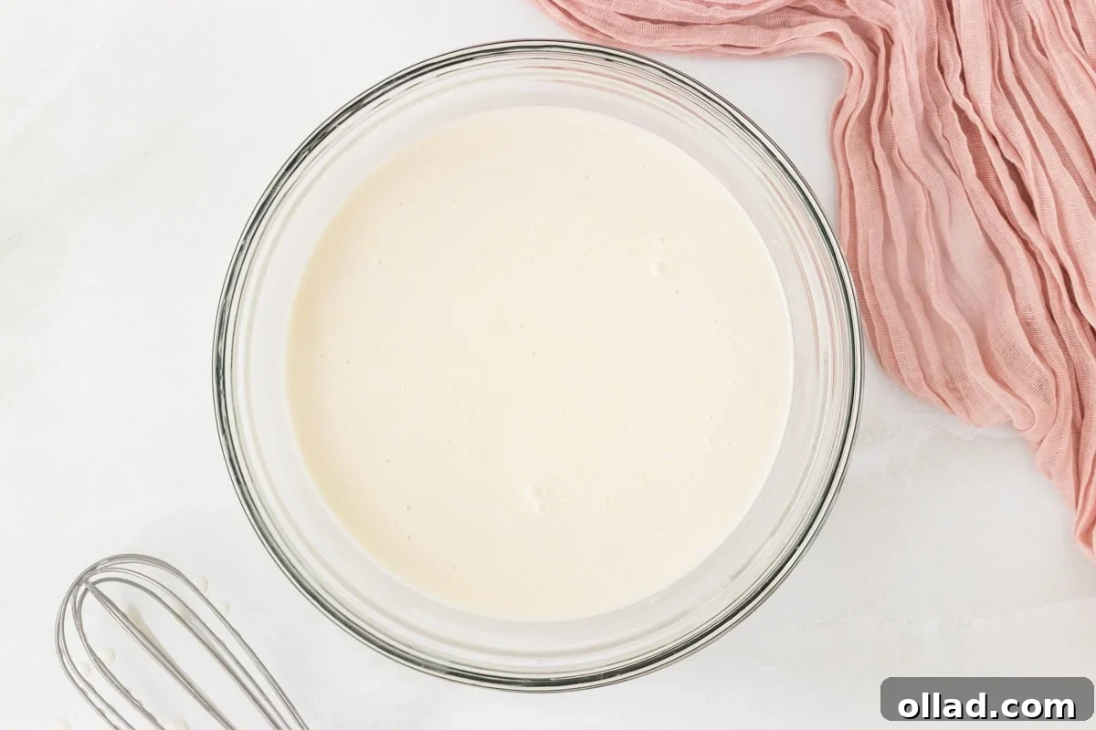 Smooth coconut sorbet mixture in a glass bowl after whisking together the ingredients.