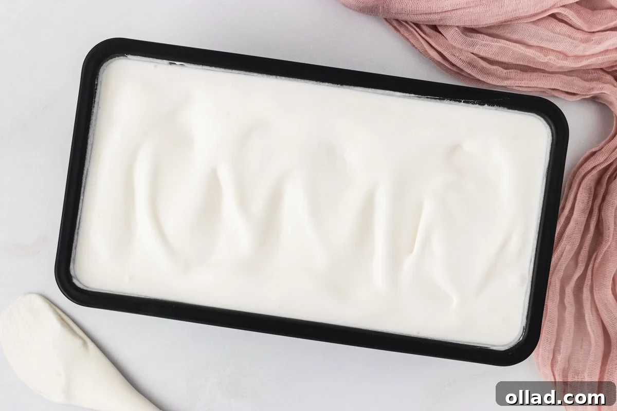 Homemade coconut sorbet spread evenly into a loaf pan after freezing.