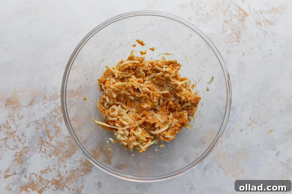 Cheese and egg mixture combined in a glass bowl for crustless tomato pie filling.