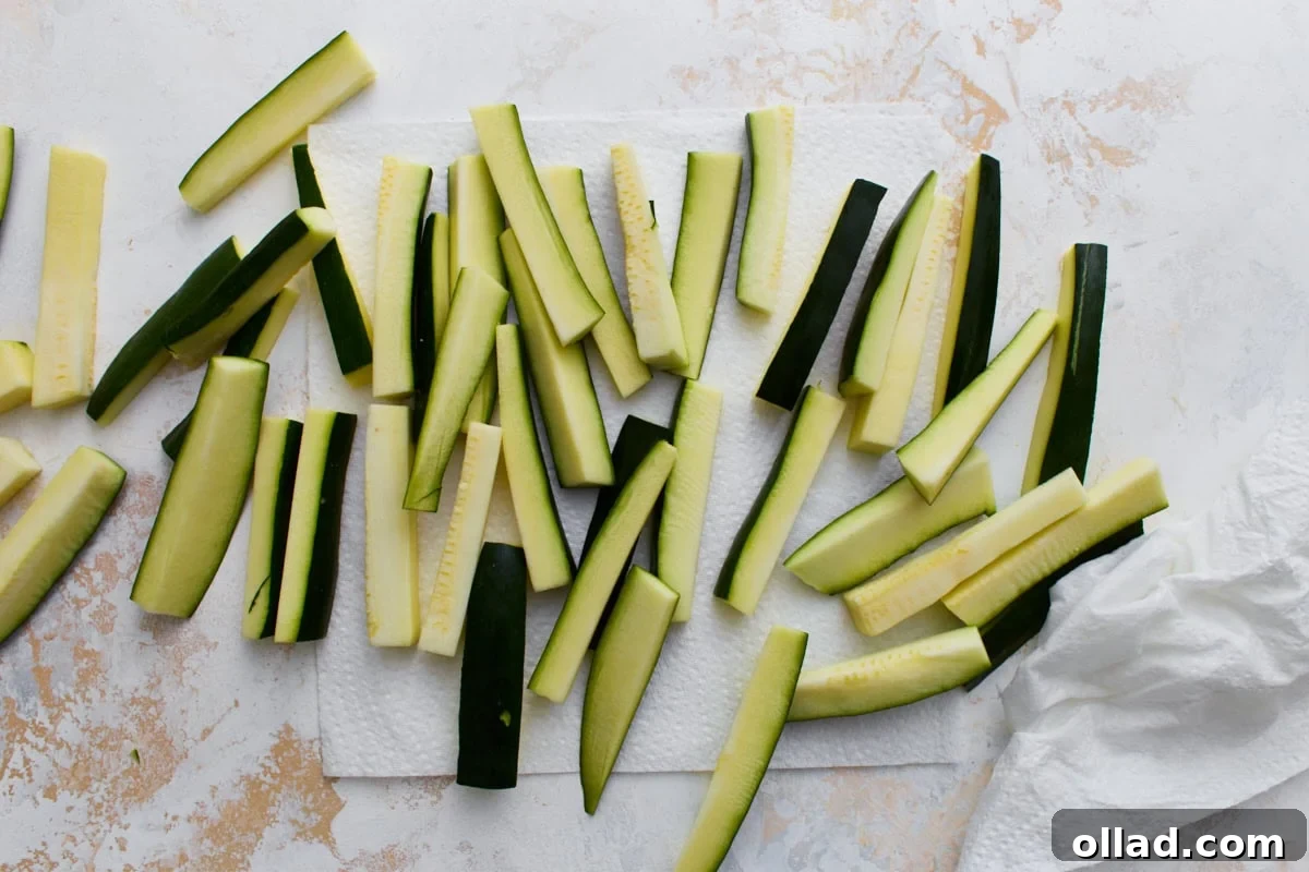Crispy Keto Zucchini Fries: Low-Carb Snack Recipe 5 Fresh zucchini cut into fry-shaped sticks drying on paper towels before breading.