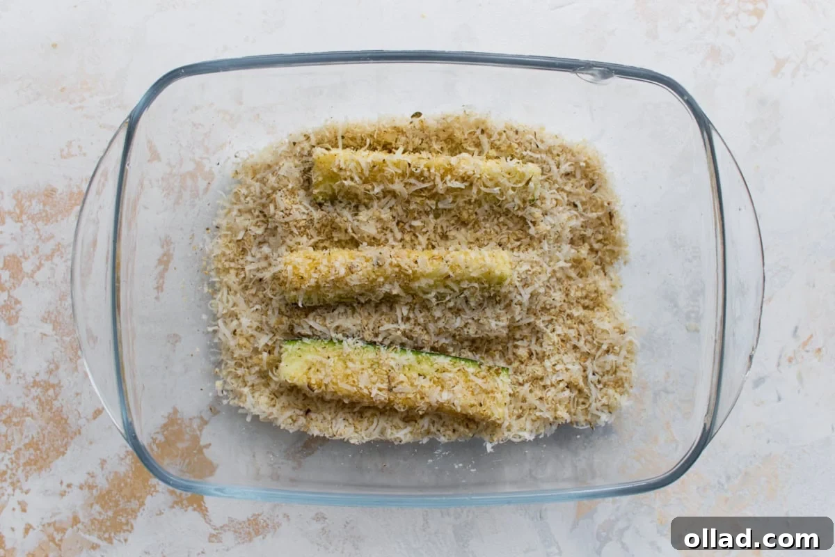 Crispy Keto Zucchini Fries: Low-Carb Snack Recipe 9 Zucchini fries coated in Parmesan and almond flour breading before baking.