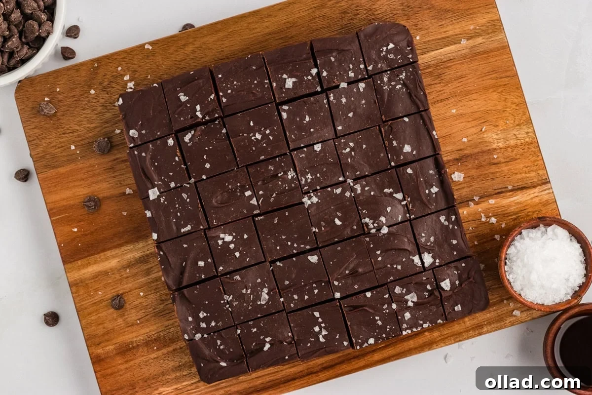 Gluten-free dairy-free chocolate fudge cut into 36 squares on a wood cutting board, sprinkled with flaky sea salt