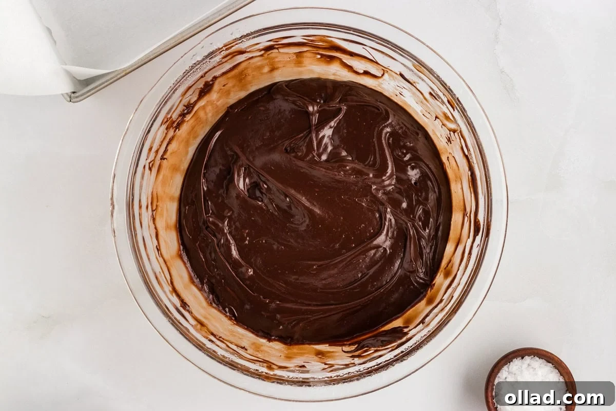 Overhead view of dairy-free chocolate fudge mixture partially melted and swirled in a glass bowl