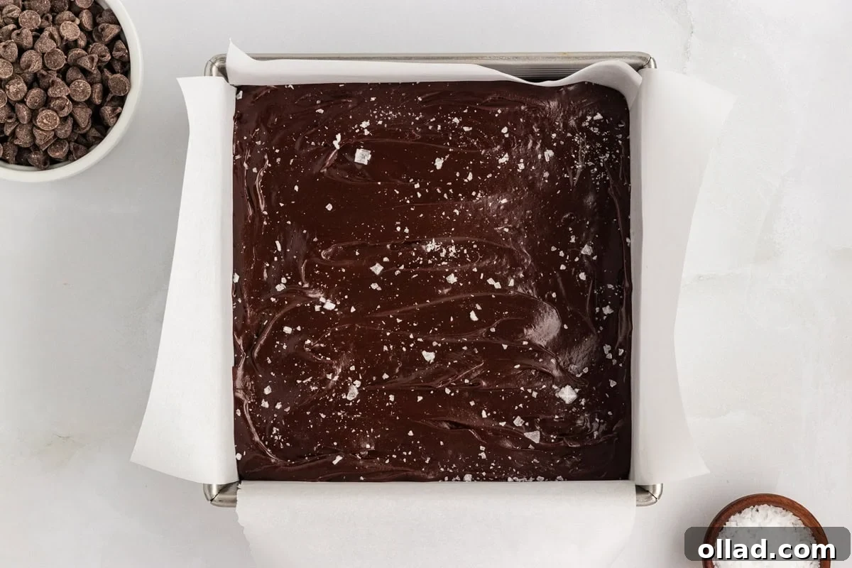 Gluten-free dairy-free chocolate fudge spread into a parchment-lined pan and topped with flaky sea salt