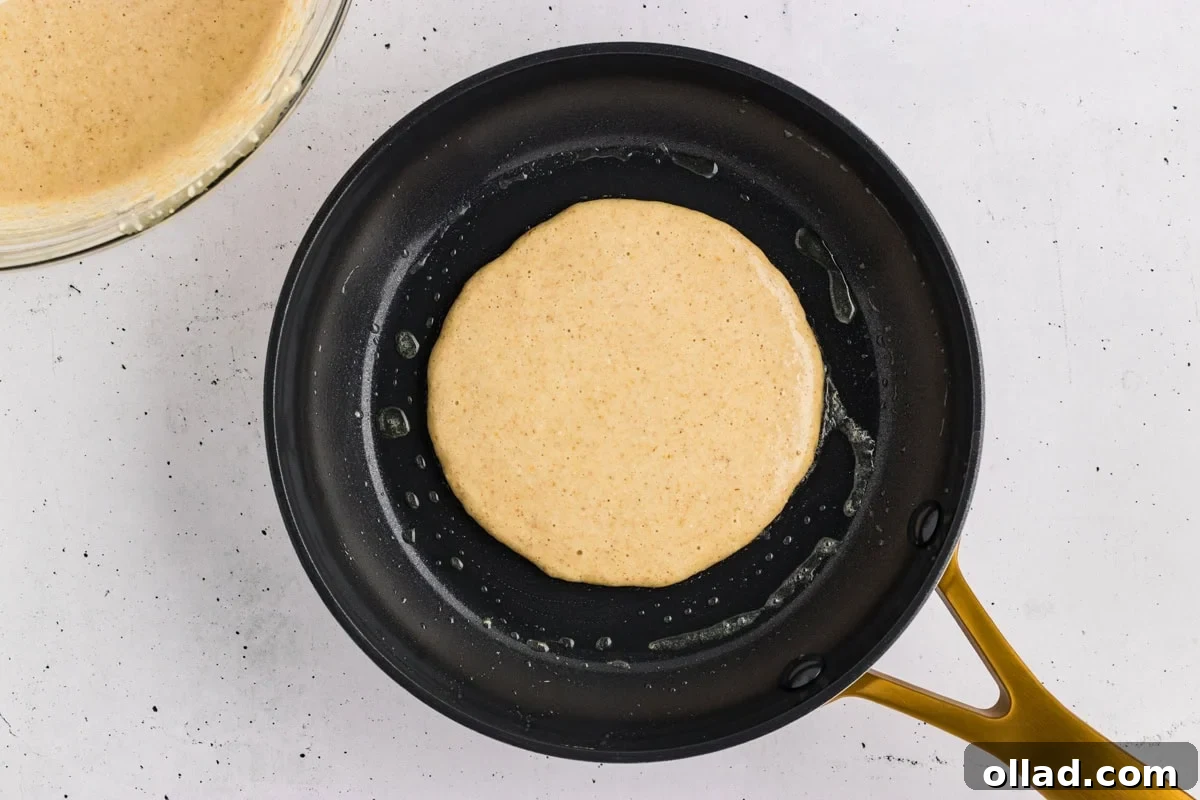 Oat flour pancake batter poured into a hot skillet.