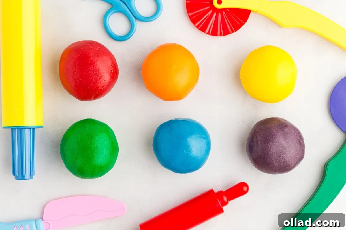 fully kneaded red, orange, yellow, green, blue, and purple play doh surrounded by kids' plastic play tools