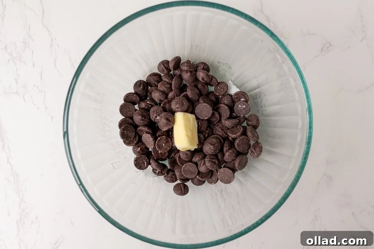 Chopped bittersweet chocolate and butter in a glass bowl, ready for hot cream to be poured over for the ganache.
