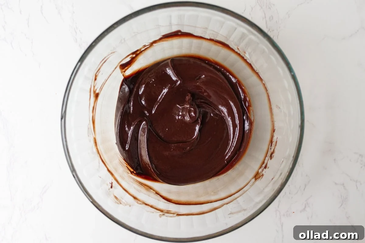 Smooth, glossy chocolate ganache in a glass bowl after melting and stirring.
