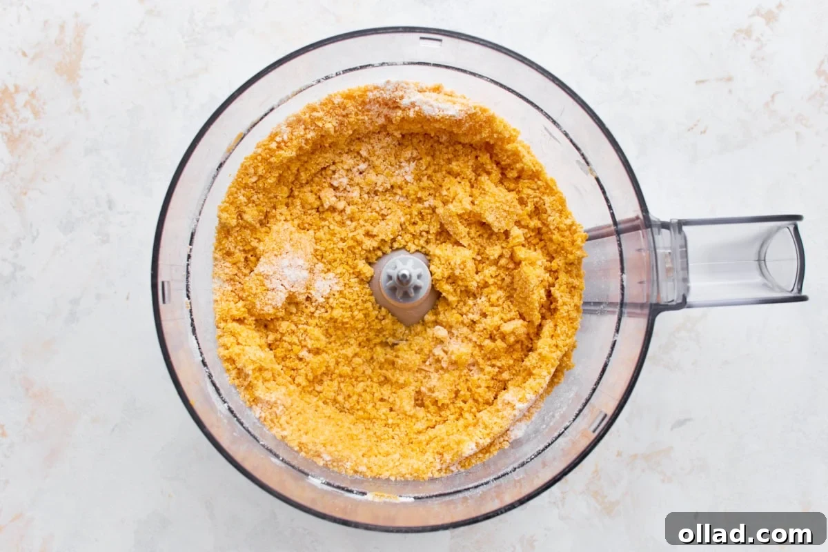 Gluten-free flour, shredded cheddar, and butter pulsed into a crumbly, sand-like texture in a food processor.