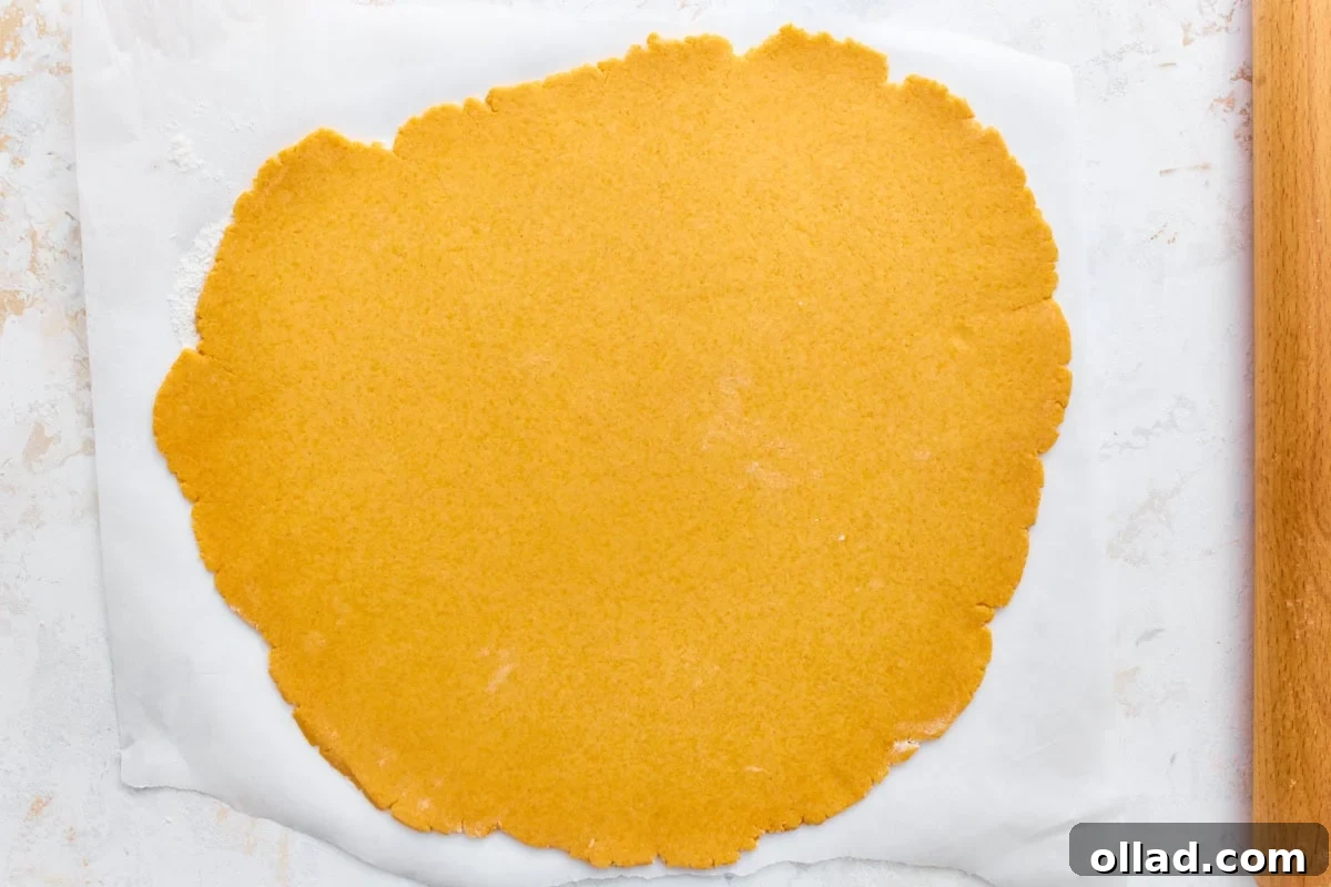 Gluten-free goldfish cracker dough rolled thin on parchment paper with a rolling pin.