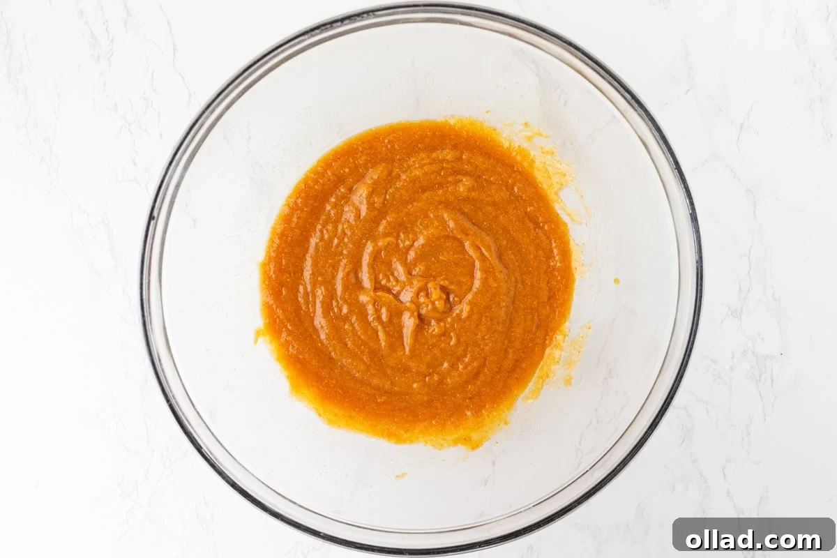 Pumpkin puree, melted butter, brown sugar, maple syrup, egg, and vanilla whisked together in a glass mixing bowl.