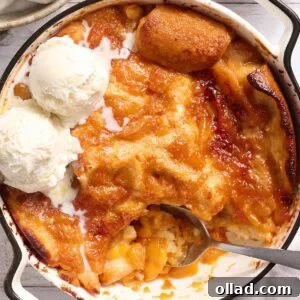 Gluten free peach cobbler in a white baking dish with scoops of vanilla ice cream
