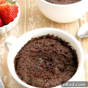 two gluten-free chocolate mug cakes with strawberries in the background