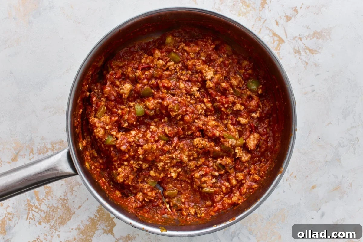 Italian sausage simmering in marinara sauce with Italian herbs in a skillet.