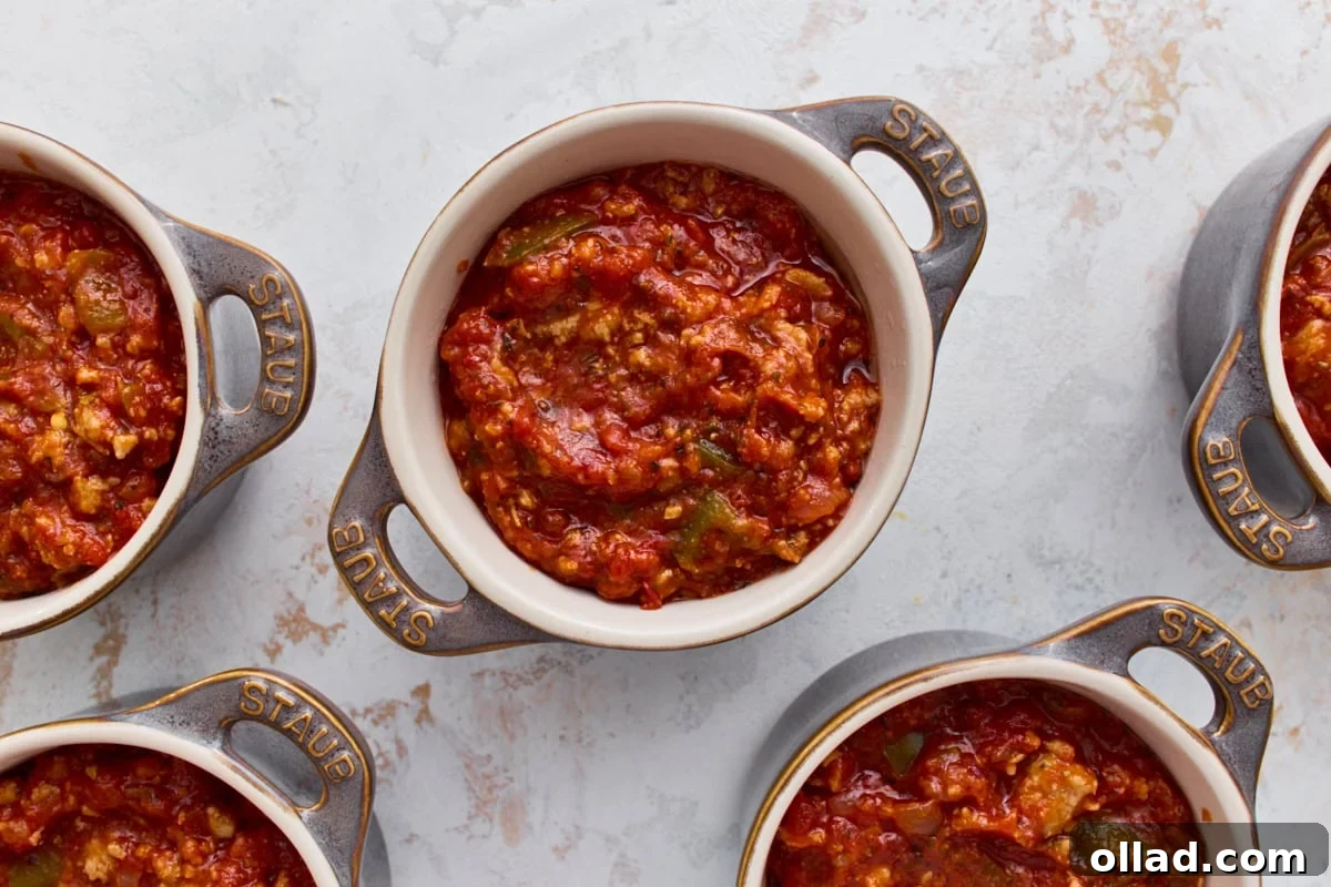 Sausage and marinara filling divided into five mini ramekins for crustless pizza bowls.