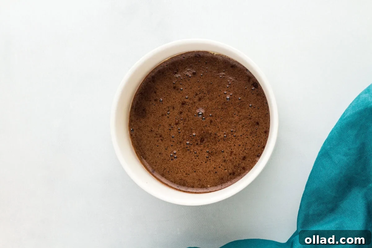 Overhead view of a flourless mug cake in a white ramekin, fresh out of the microwave