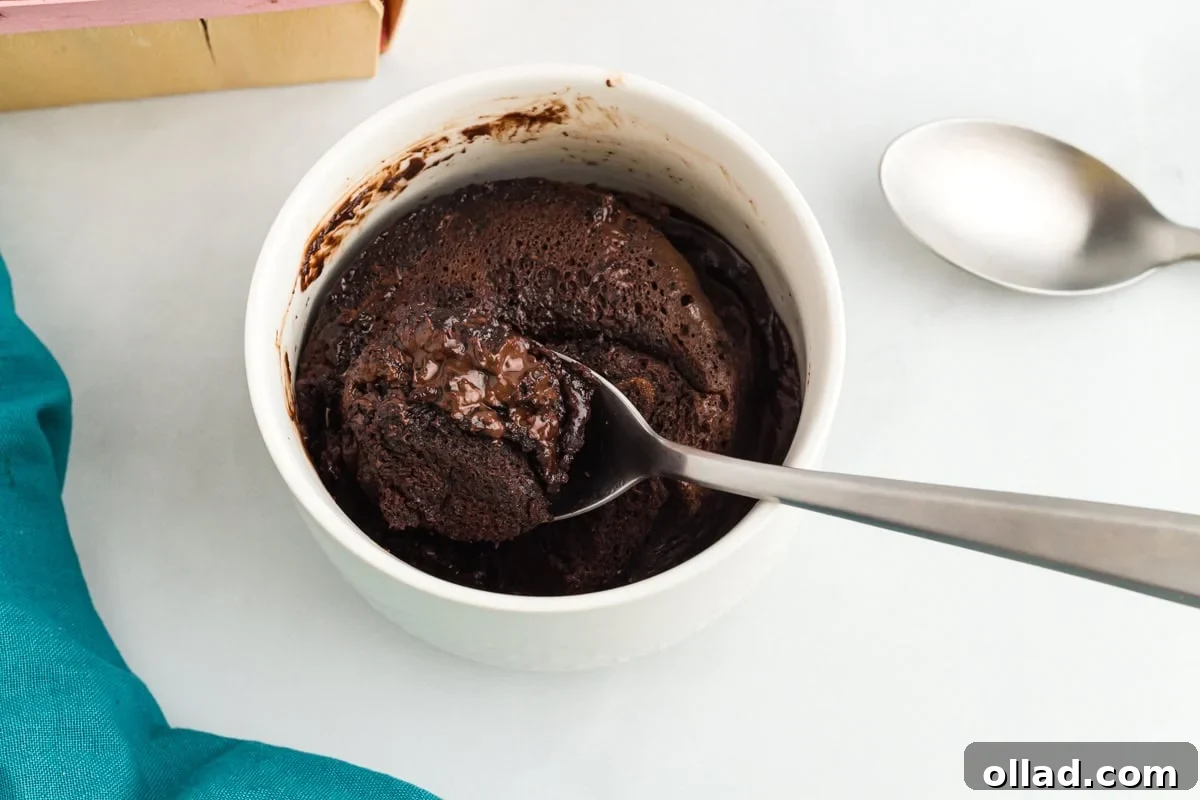 A spoon digging into a flourless mug cake, showing the fudgy, molten center