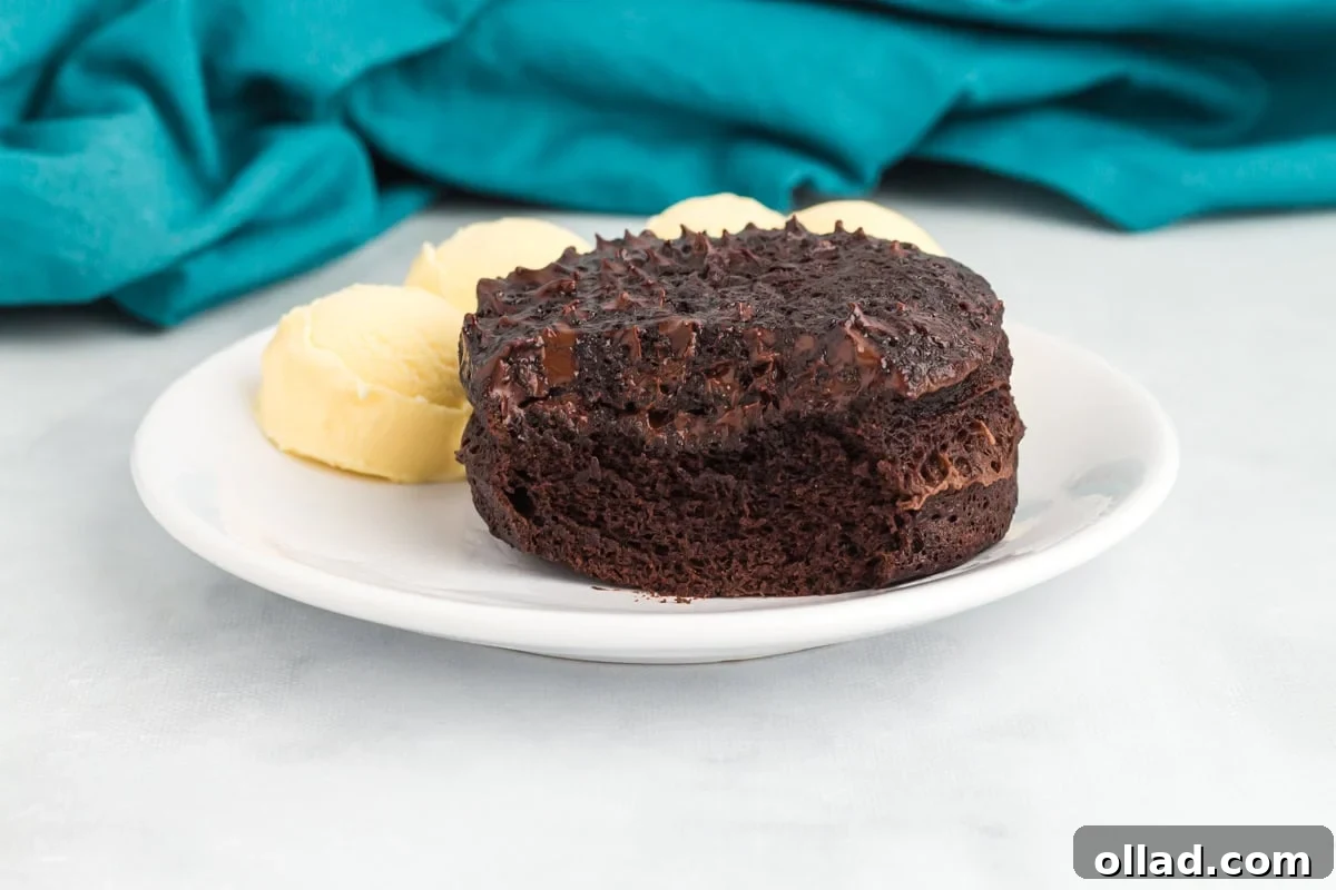 Flourless mug cake turned out onto a plate and served with scoops of vanilla ice cream